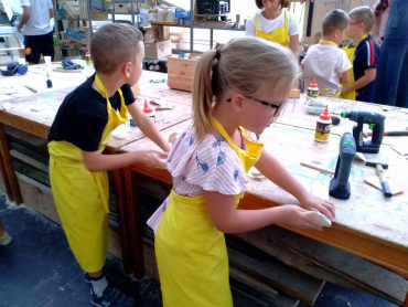 Dzieci podczas warsztatów z majsterkowania szlifują drewniane elementy
